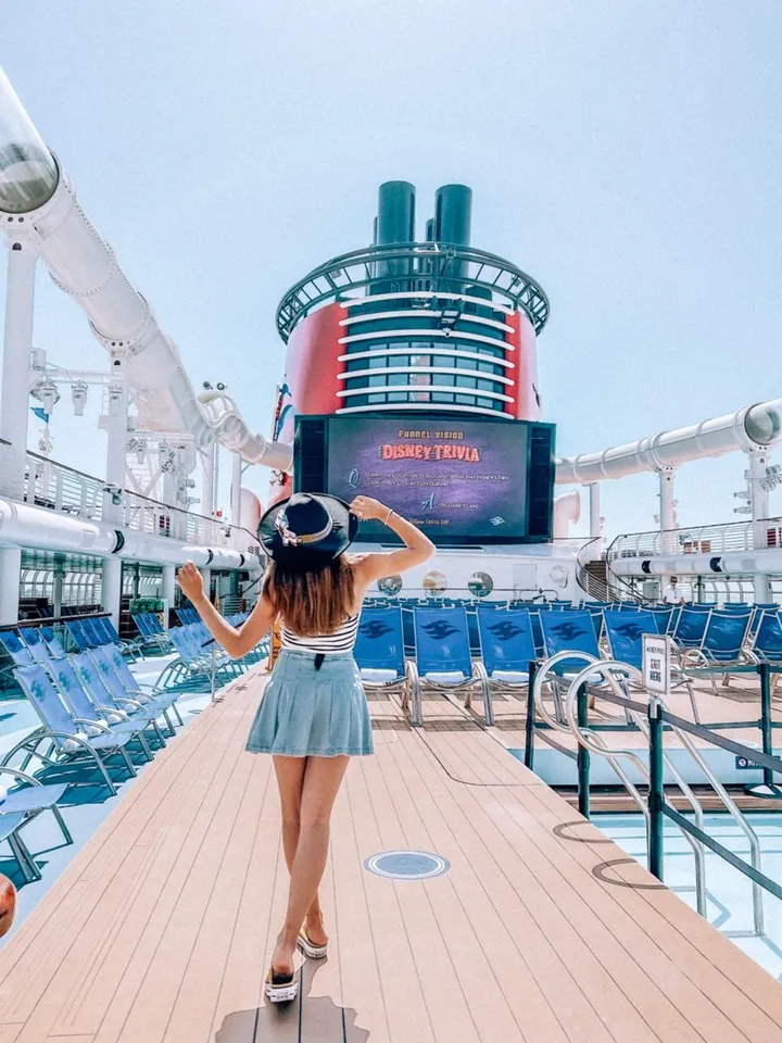 Sofi en la cubierta de un crucero Disney, frente a la pantalla gigante y la chimenea