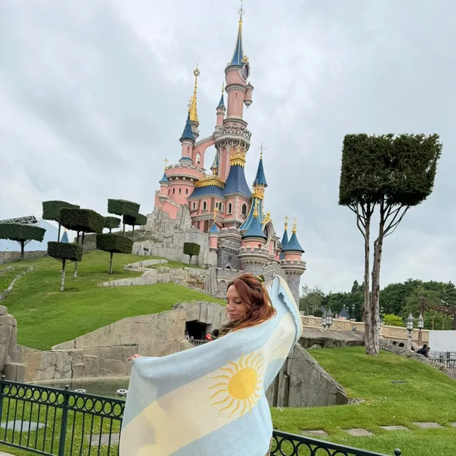 Sofi con la bandera argentina frente al castillo de Disneyland París